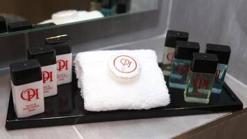 Una bandeja con botellas de loción corporal, una toalla blanca y un dispensador de gel antibacterial.