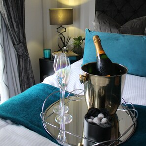 A bed with a champagne bottle, a glass, and a tray. - The Old Hall Hotel (Coventry)
