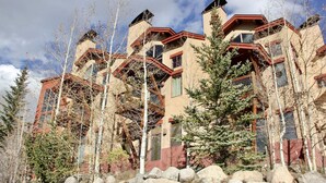 A multi-story building with a unique architectural design, featuring a mix of red and beige colors, and surrounded by trees and rocks. - Mountain-View Condo in Dillon • Walk to Dining & Lake • Close to Keystone (Dillon)