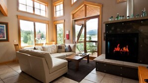 A spacious living room with a fireplace, large windows, and a view of the outdoors. - Mountain-View Condo in Dillon • Walk to Dining & Lake • Close to Keystone (Dillon)