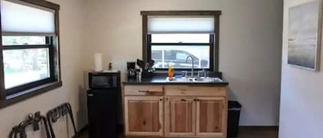 A compact kitchen with wooden cabinets, a microwave, and a sink.