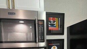 Cuina amb microones Maytag, fogó i cafetera. Hi ha dos quadres penjats a la paret.