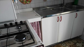 A kitchen with a gas stove, white cabinets, and a tiled backsplash.