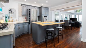 A modern kitchen with grey cabinets, a central island, and a dining area with chairs.