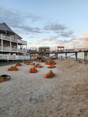 Une jetée au bord de la plage, avec un bâtiment doté de balcons et illuminé de guirlandes lumineuses.