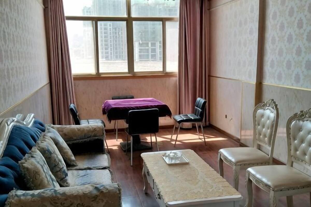 A room with a sofa, chairs, a table, and a window with curtains.