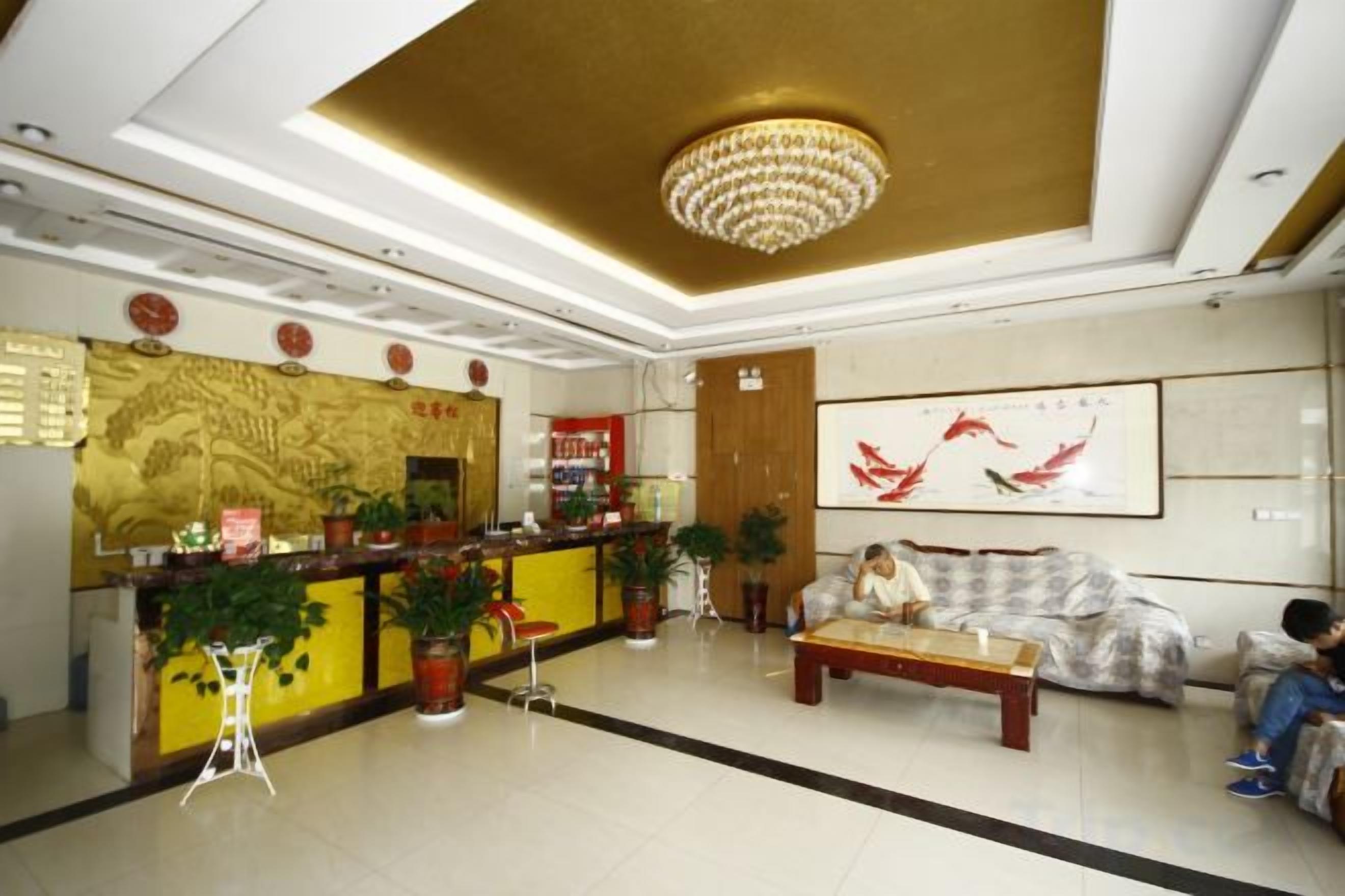 A hotel lobby with a reception desk, seating area, and a large painting on the wall.