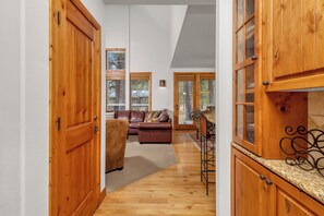 A hallway with wooden doors, a brown leather sofa, and a dining area with a metal chair and table.