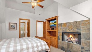 A bedroom with a bed, a television, a fireplace, and a ceiling fan. - Elegant, sleep 8, private hot tub, gourmet kitchen (Sunriver)