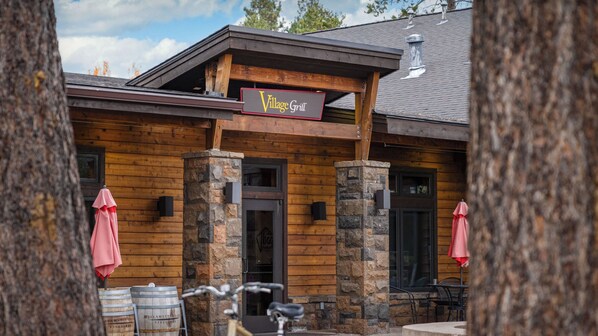 A wooden building with a sign reading 'Village Grill' and stone pillars.