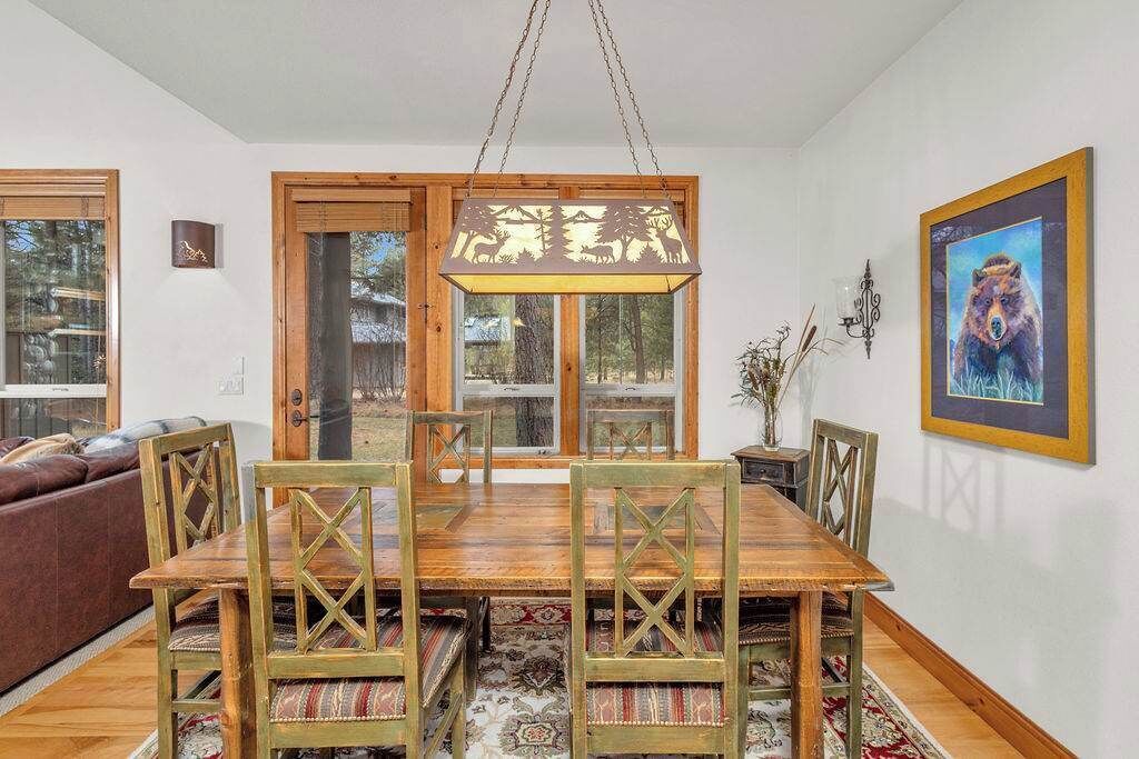 A dining area with a wooden table and chairs, a hanging light fixture, and a framed picture on the wall.