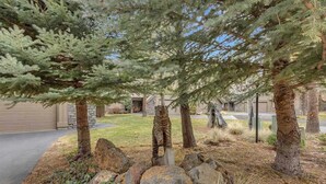 A residential driveway with a stone pathway, large rocks, and evergreen trees. - Elegant, sleep 8, private hot tub, gourmet kitchen (Sunriver)