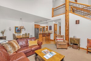 A spacious living area with a leather sofa, a wooden coffee table, and a staircase leading to an upper level.