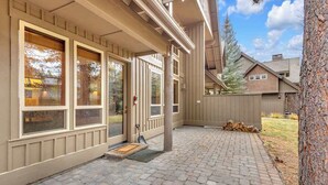 A house with a covered patio, large windows, and a wooden fence. - Elegant, sleep 8, private hot tub, gourmet kitchen (Sunriver)