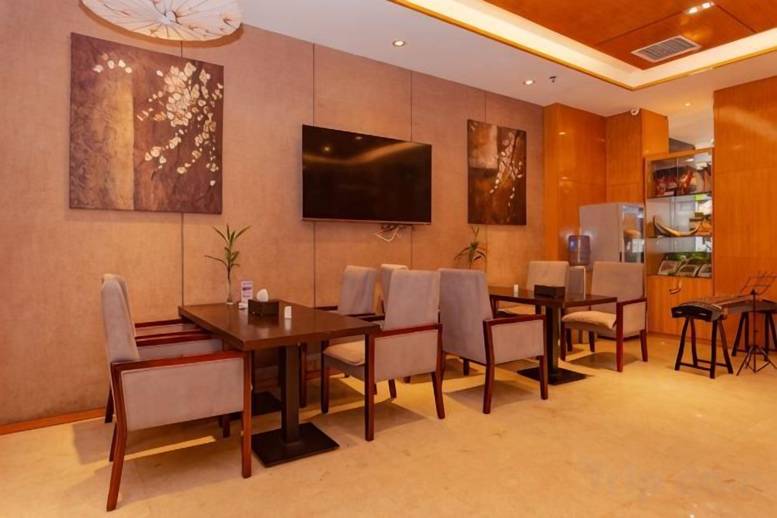 A hotel room with a dining area, a flat-screen TV mounted on the wall, and a minibar.