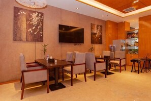 A hotel room with a dining area, a flat-screen TV mounted on the wall, and a minibar. - Kailisi Army for the Hotel (Zunyi)
