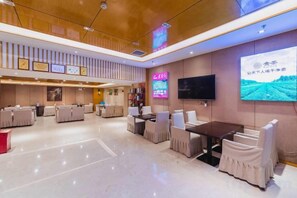 A hotel lobby with multiple seating areas, a flat-screen TV, and a large digital screen displaying a landscape. - Kailisi Army for the Hotel (Zunyi)