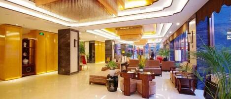 A spacious lobby with a reception desk, seating area, and a large window providing a view of the outside.