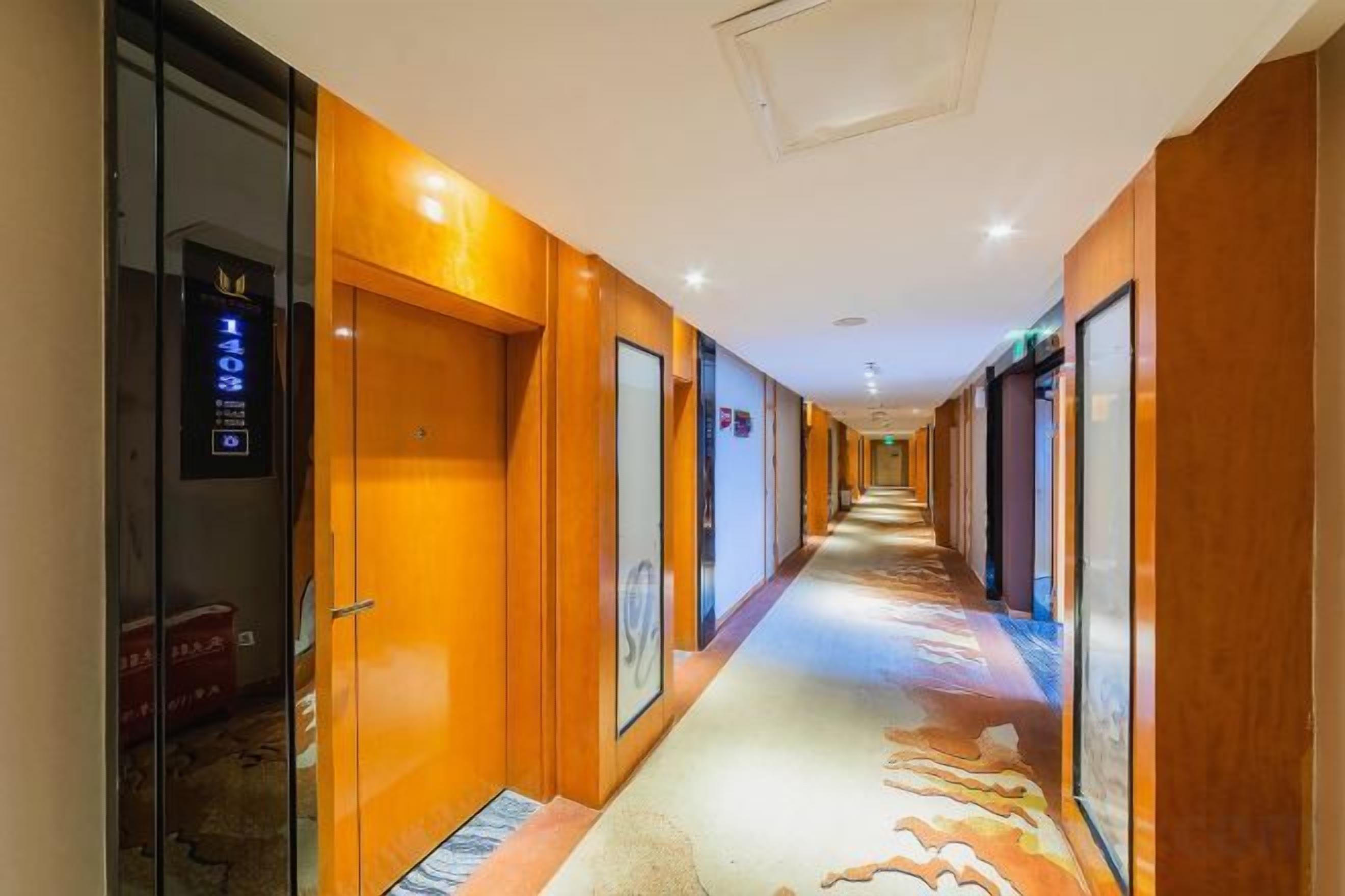 A hotel corridor with doors on both sides, a patterned carpet, and a ceiling light fixture.