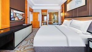 Habitación de hotel con una cama grande, un televisor de pantalla plana montado en la pared y un diseño de paneles de madera.