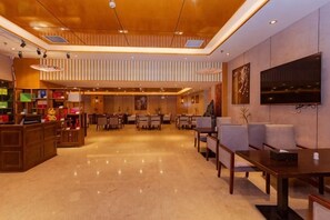 A hotel lobby with a reception desk, seating area, and a television mounted on the wall. - Kailisi Army for the Hotel (Zunyi)