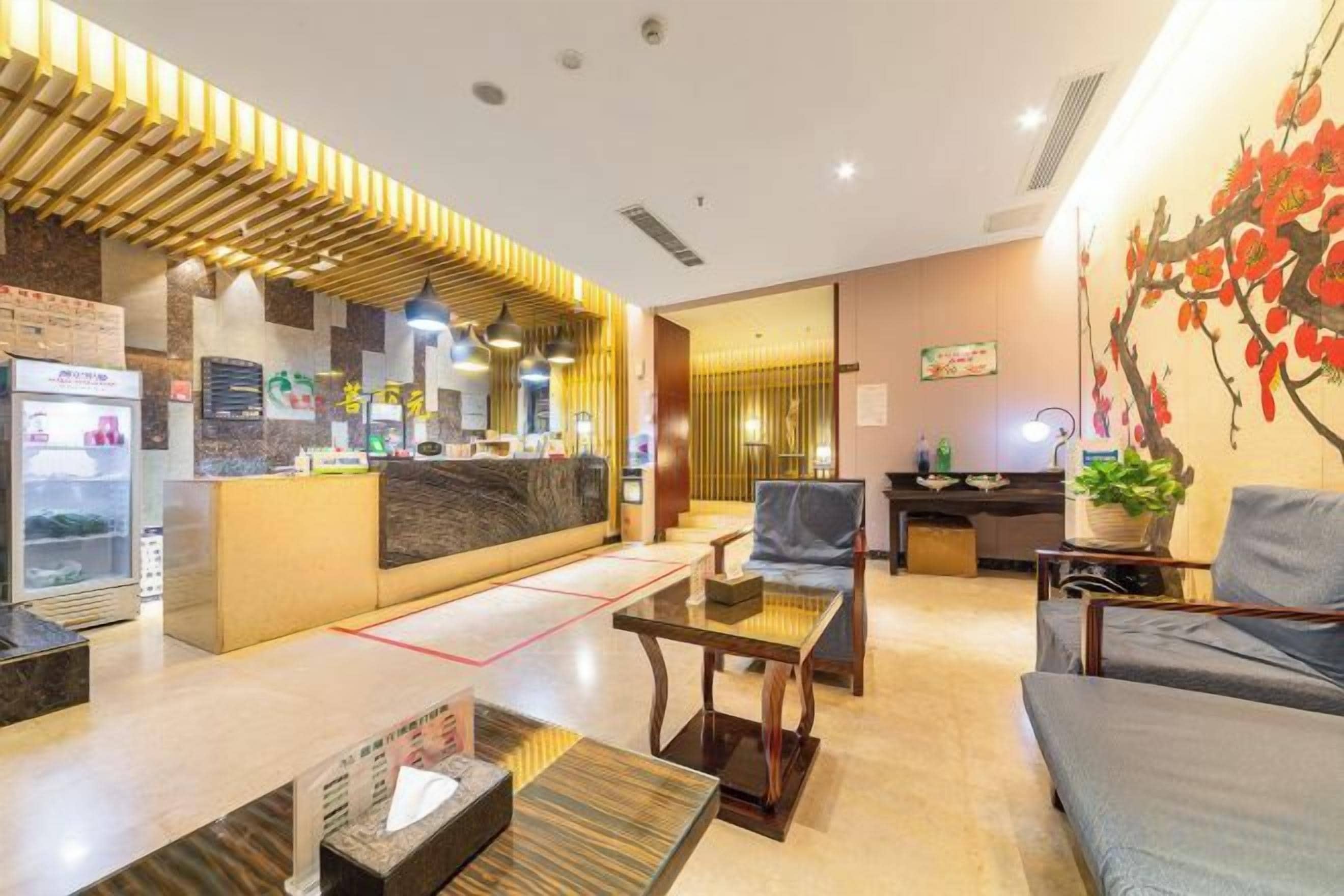 Un vestíbulo de hotel con mostrador de recepción, zona de estar y televisor en la pared.