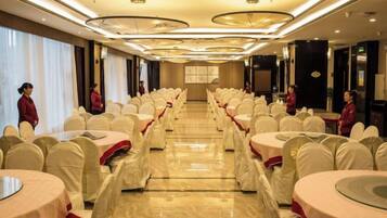A banquet hall with round tables, chairs, and a long table down the center.