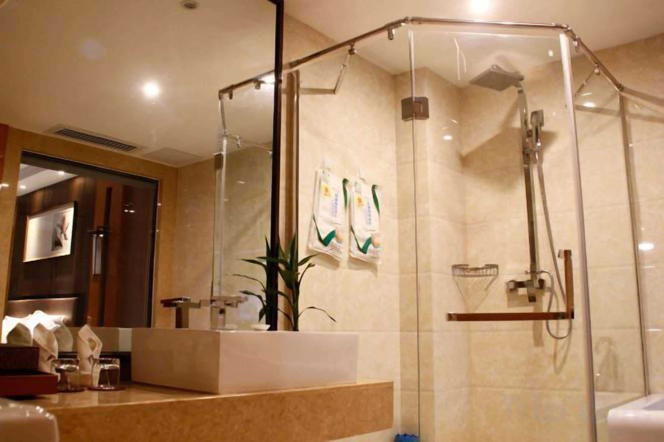 Une salle de bain moderne avec une douche à parois de verre, un grand miroir et un plan de toilette avec des articles de toilette.