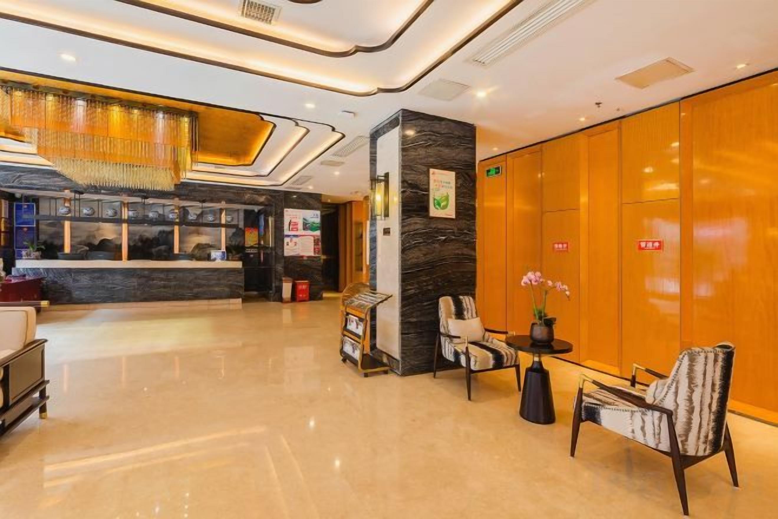 A hotel lobby with a reception desk, seating area, and a large wooden wall.