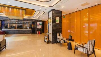 A hotel lobby with a reception desk, seating area, and a large wooden wall.
