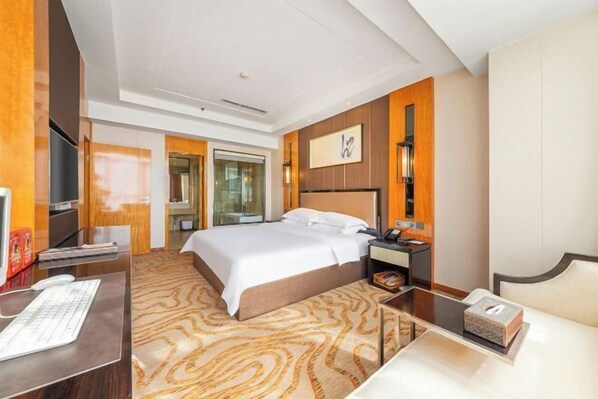 A hotel room with a large bed, a desk with a computer, a bedside table with a lamp, and a TV. - Kailisi Army for the Hotel (Zunyi)