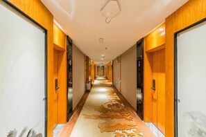 A hotel hallway with a patterned carpet, wooden walls, and doors on both sides. - Kailisi Army for the Hotel (Zunyi)