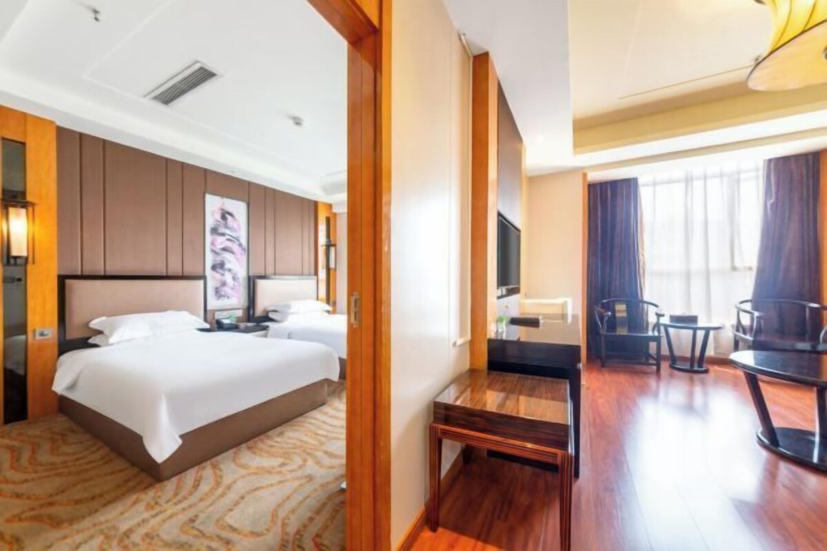 A hotel room with a large bed, a desk, a chair, and a television.