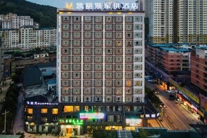 A multi-story hotel with a grid of windows, a prominent sign at the top, and a street view with shops and vehicles. - Kailisi Army for the Hotel (Zunyi)