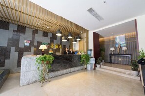 A hotel reception area with a reception desk, two receptionists, and a modern interior design. - Kailisi Army for the Hotel (Zunyi)
