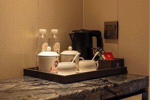 Ein Tablett mit einer Kaffeemaschine, einem Teekessel und zwei Tassen auf einer Marmorplatte.