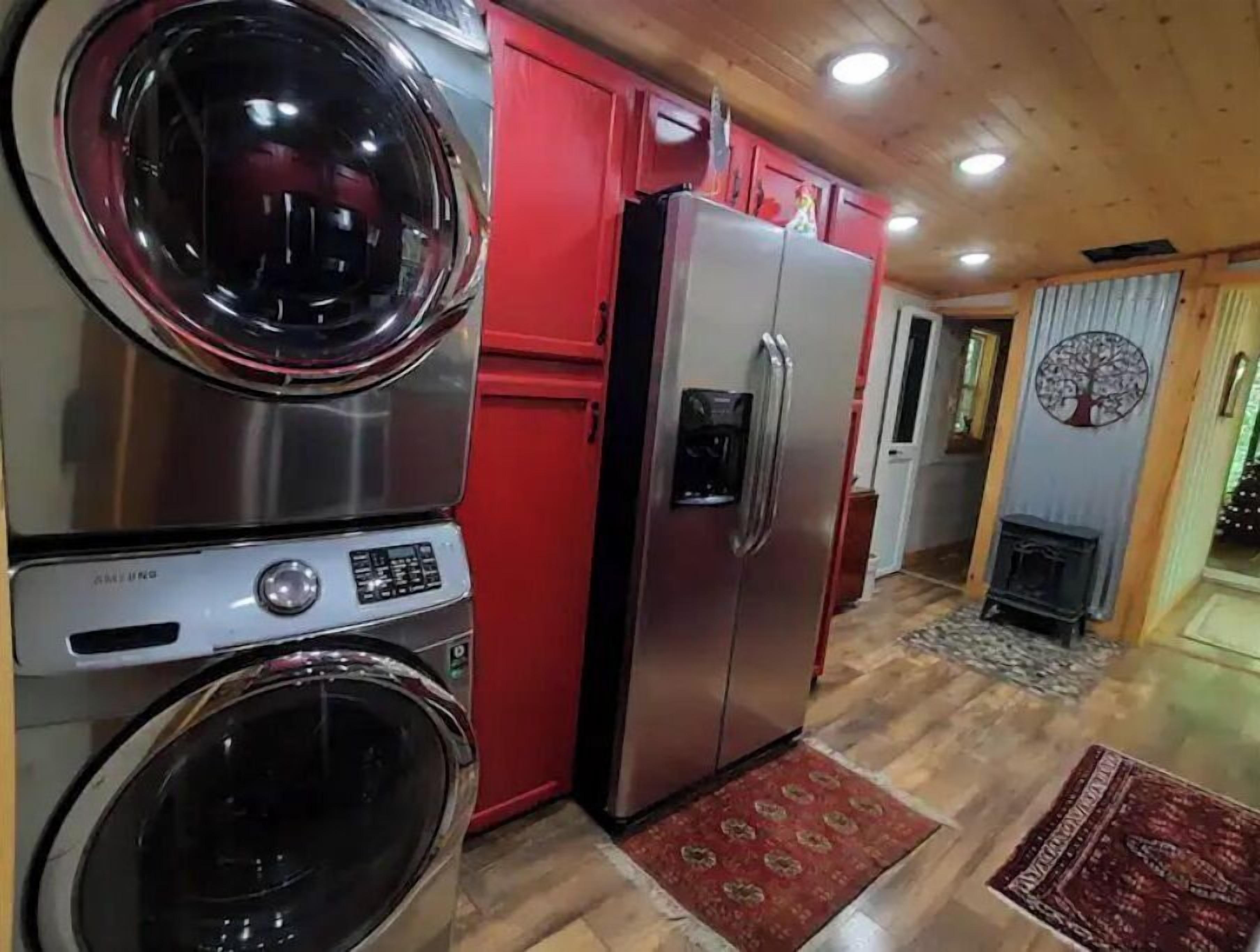 A compact kitchen with a stainless steel washer, a refrigerator, and a red cabinet.