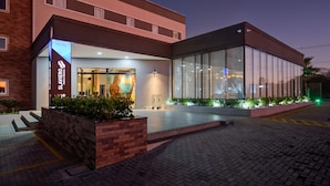 Entrada de hotel con diseño moderno, recepción a la vista y un jardín ajardinado.
