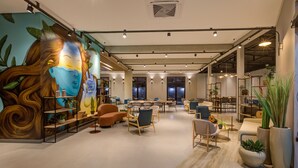 Un interior moderno con un mural, zonas de estar y plantas de interior.