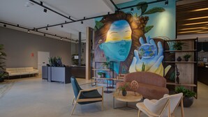 Un vestíbulo moderno con mostrador de recepción, zona de estar y un gran mural.