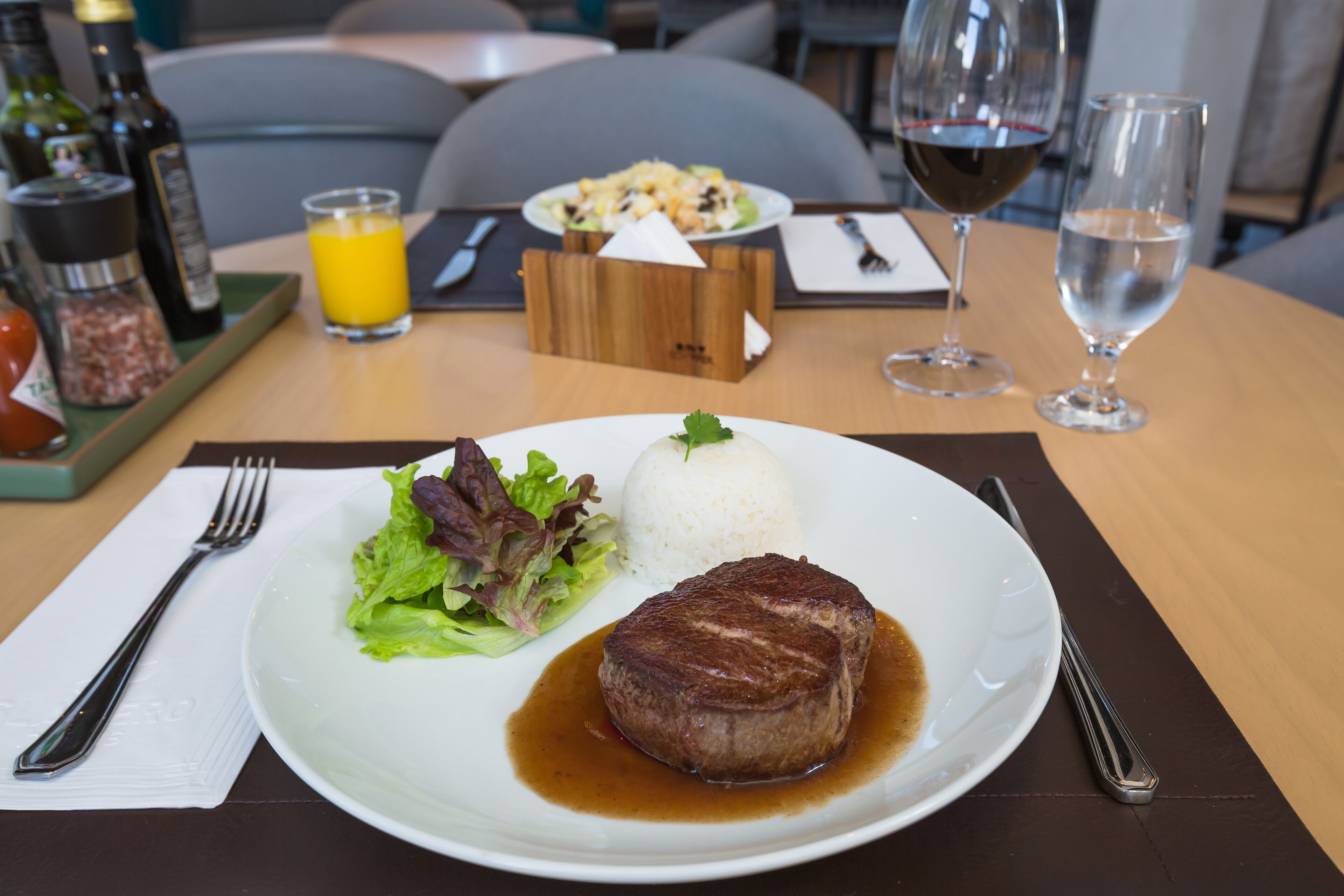 Une table à manger avec une assiette de nourriture, un verre de jus de fruits et une bouteille de vin.
