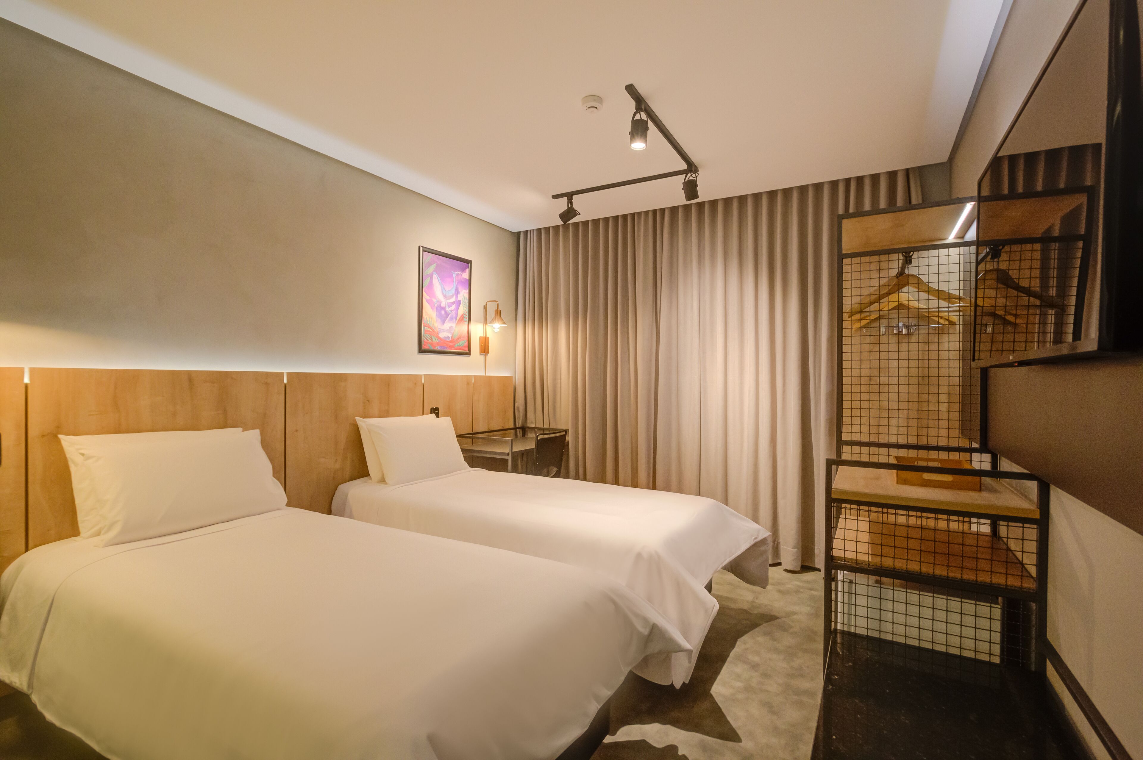 Una habitación de hotel con dos camas, un escritorio, un armario y un cuadro en la pared.
