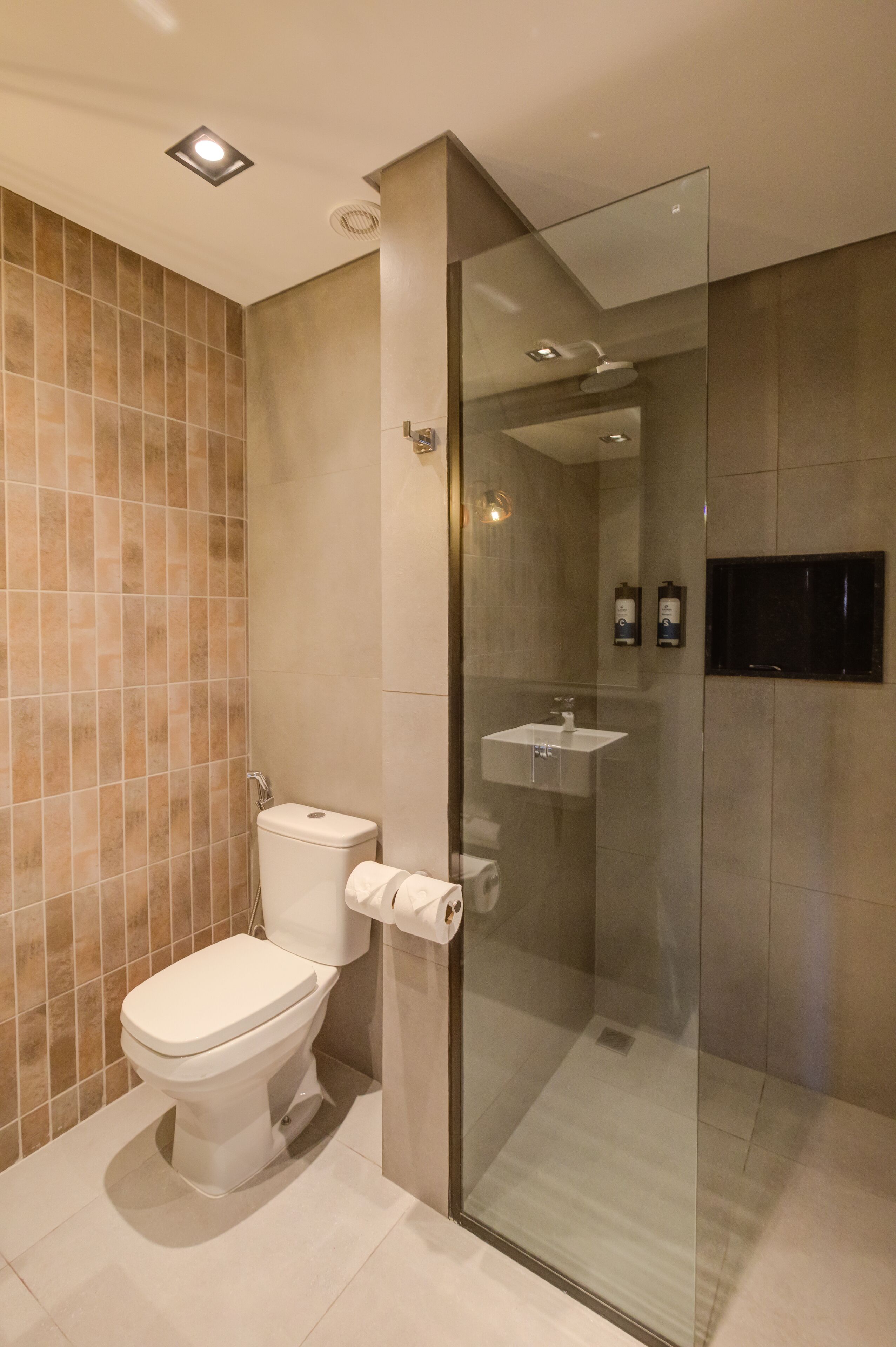 Un baño moderno con ducha acristalada, inodoro y lavamanos.