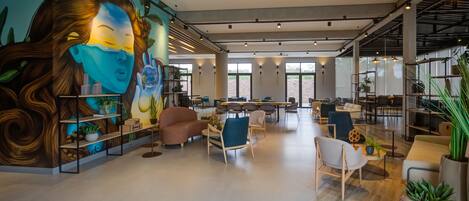 A spacious lobby with modern furniture, a large mural, and natural light from large windows.