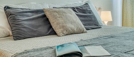 A neatly made bed with a quilted cover, two pillows, and a book on it.