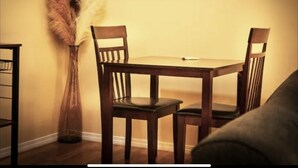 Un coin repas avec une table et des chaises en bois, un vase contenant des plumes séchées et une bibliothèque.
