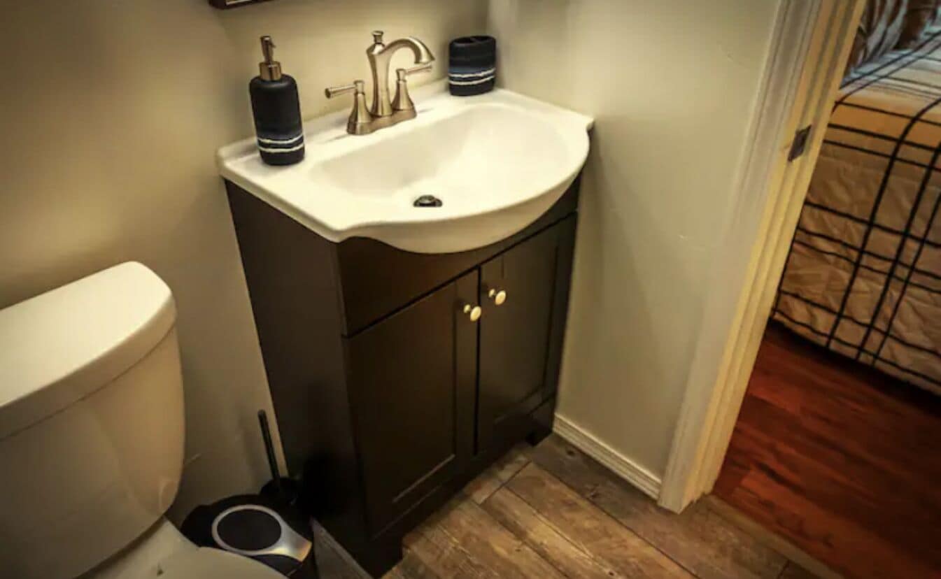 A bathroom with a white sink, dark cabinets, and a toilet.