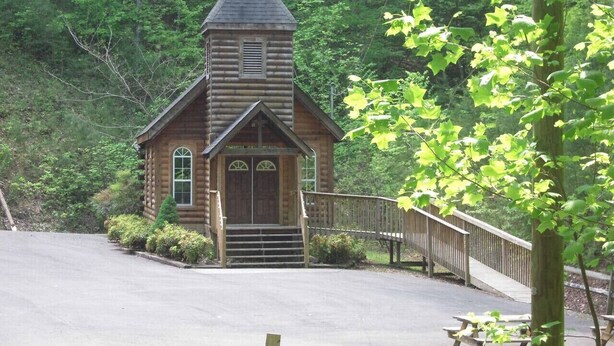 A small wooden cabin with a steeply pitched roof, a front door, and a small porch. - Countryside in Country Pines (Sevierville)