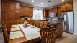 Una cucina moderna con mobili in legno, un frigorifero in acciaio inossidabile e un'area pranzo con tavolo apparecchiato per quattro persone.