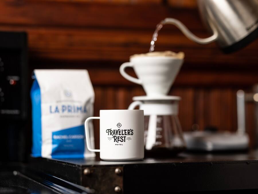 Een koffiezetapparaat, een koffiekop en een zak koffiebonen op een tafel.